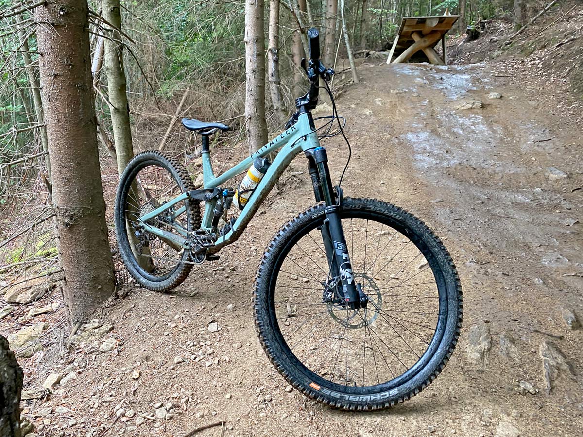 Privateer 141 all-mountain trail bike, affordable alloy 29er trail enduro all-mountain bike, trail side Bike against a tree
