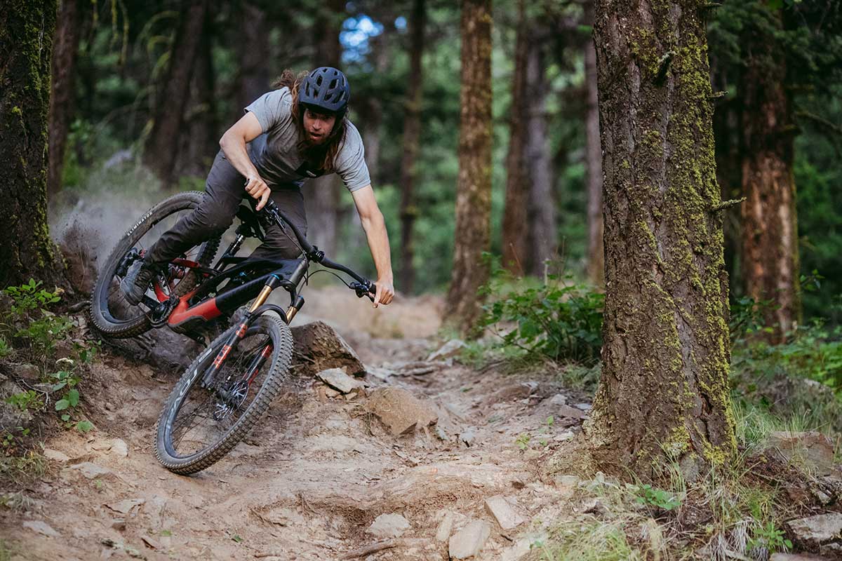 mountain biker riding new specialized stumpjumper evo 150mm trail bike sideways between trees