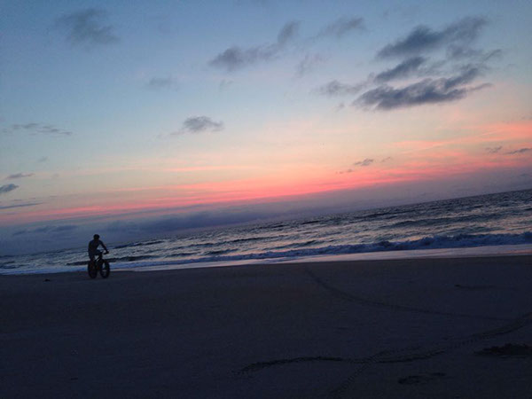 Fat Bike riding across the beach at sunset