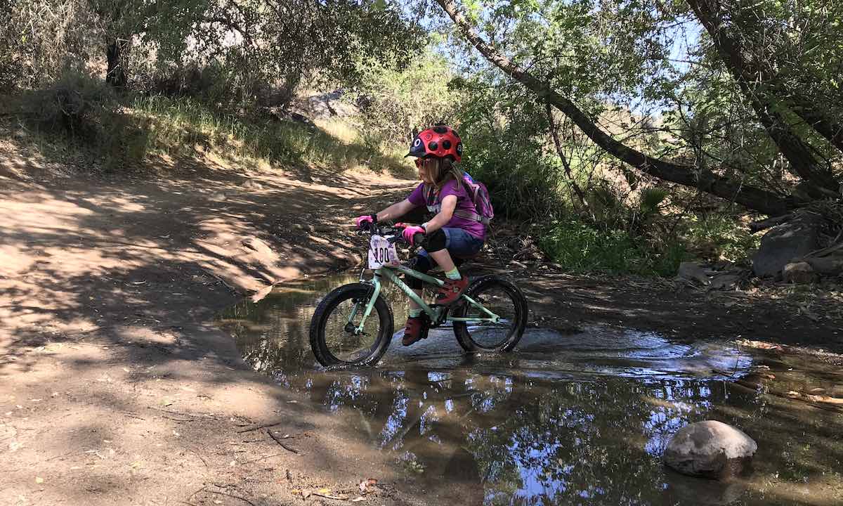 bikerumor pic of the day Kerry Waldman with Grom crossing the creek on her pedal bike.