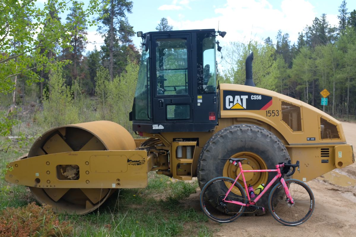 bikerumor pic of the day pink feather bicycle next to cat tractor road roller in boulder, colorado.
