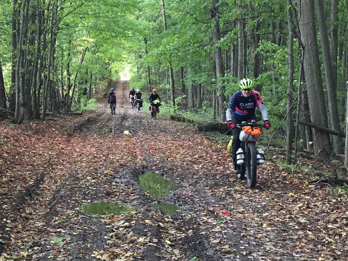 bikerumor pic of the day a group of cyclists bike packing in Niagara Escarpment in Southern Ontario, surrounded by fall leaves on the dirt road.