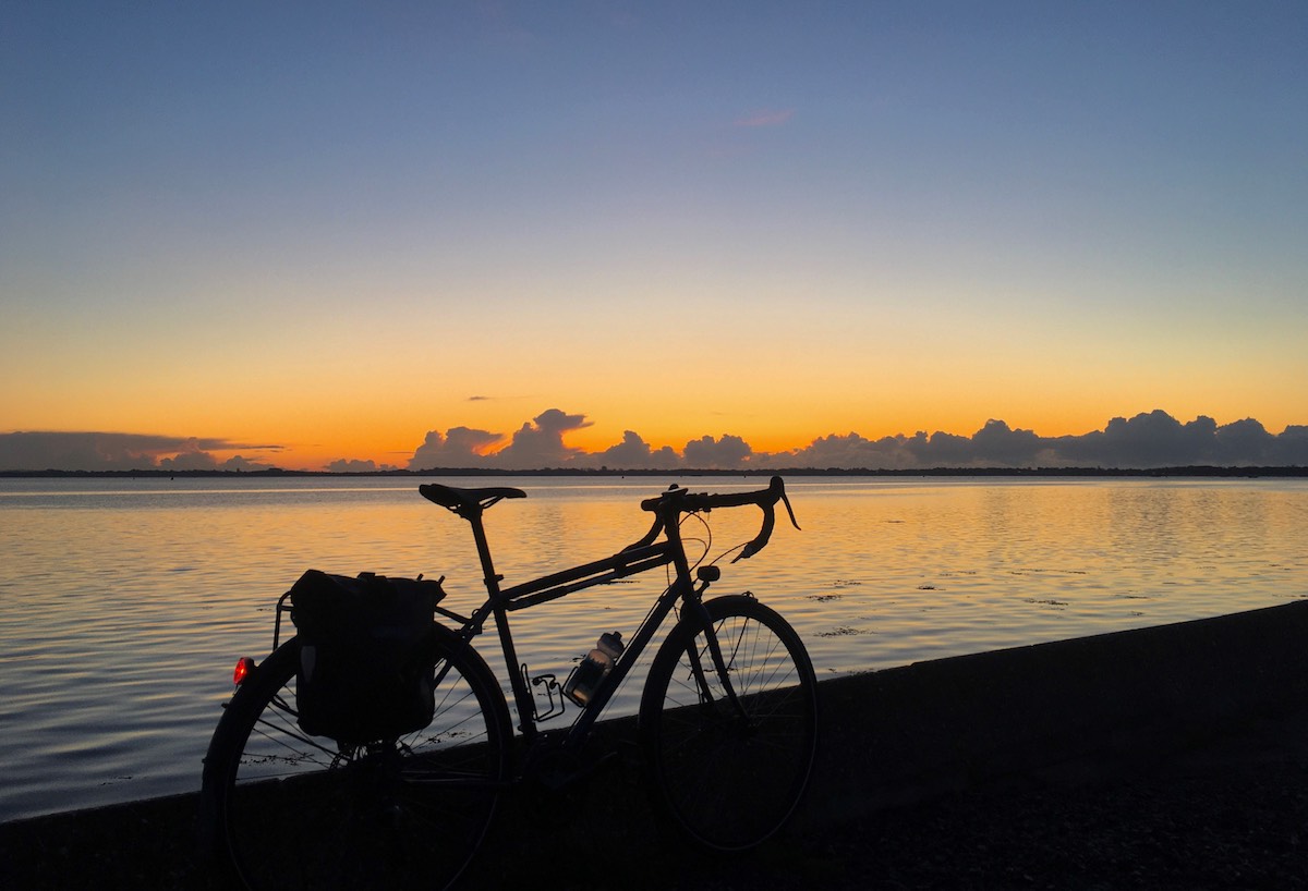 bikerumor pic of the day silhouette of a commuter bicycle against a body of water reflecting the sunrise in Portsmouth, UK.