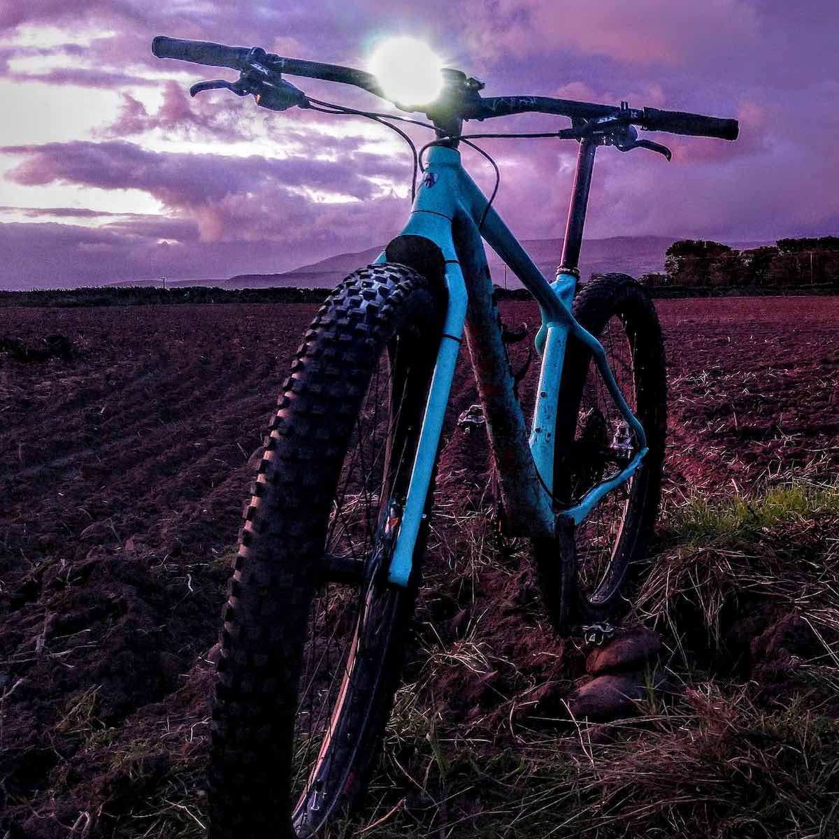bikerumor pic of the day teal trek stache facing camera in a dark field with purple sky behind it on the isle of man.