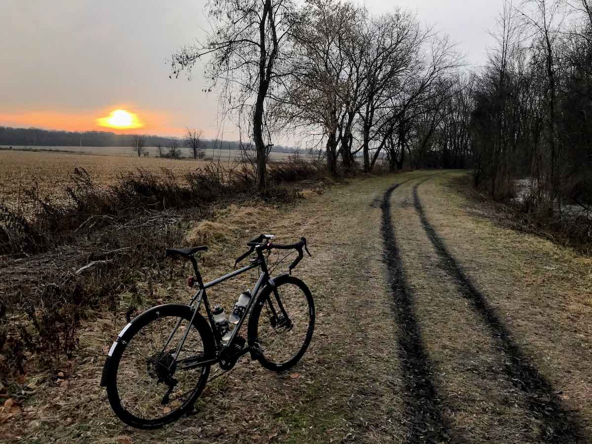 bikerumor pic of the day black bicycle on winter trail with orange sunrise peeking out from the horizon on the Genesee Valley Greenway Trail, New York State