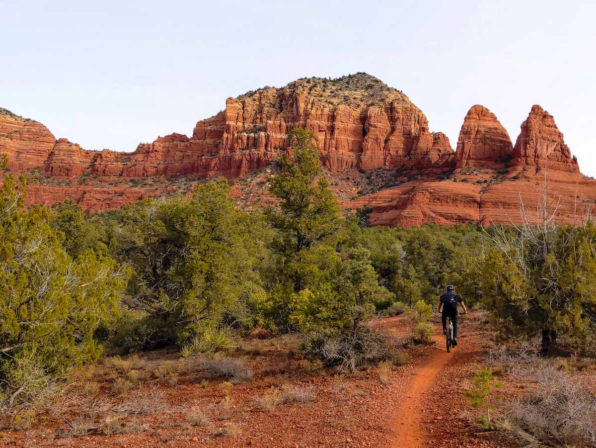 bikerumor pic of the day sedona arizona cyclist riding on red dirt trail through pine trees and shrubs towards red mountains