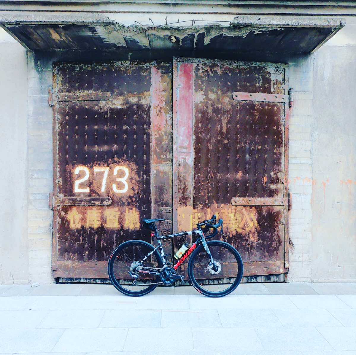 bikerumor pic of the day bicycle leaning against rusty warehouse door in Shanghai-Pudong, China on the Bund.