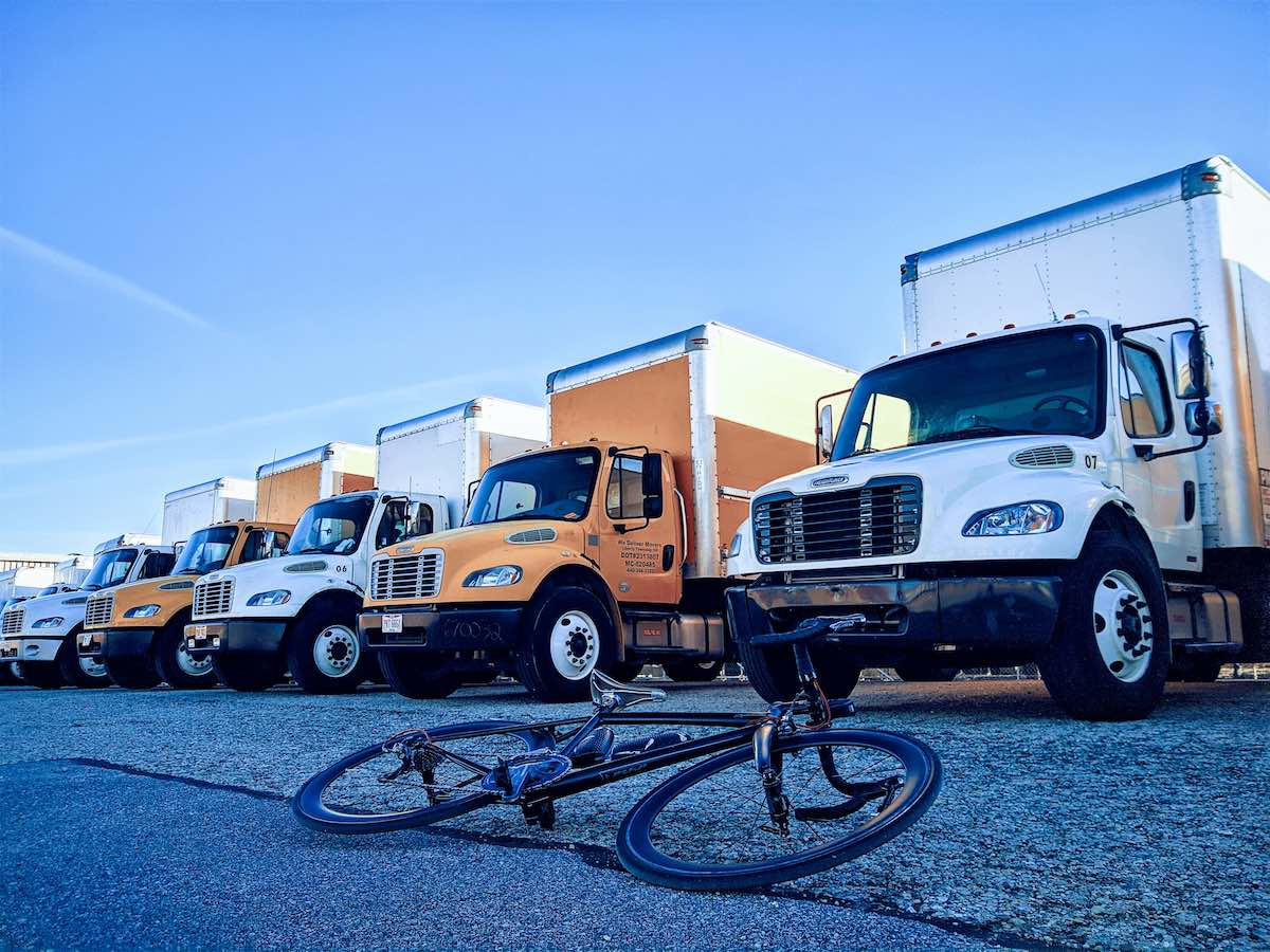 bikerumor pic of the day cincinnati ohio, bicycle laying on the road in front of large delivery trucks alternating white and yellow.
