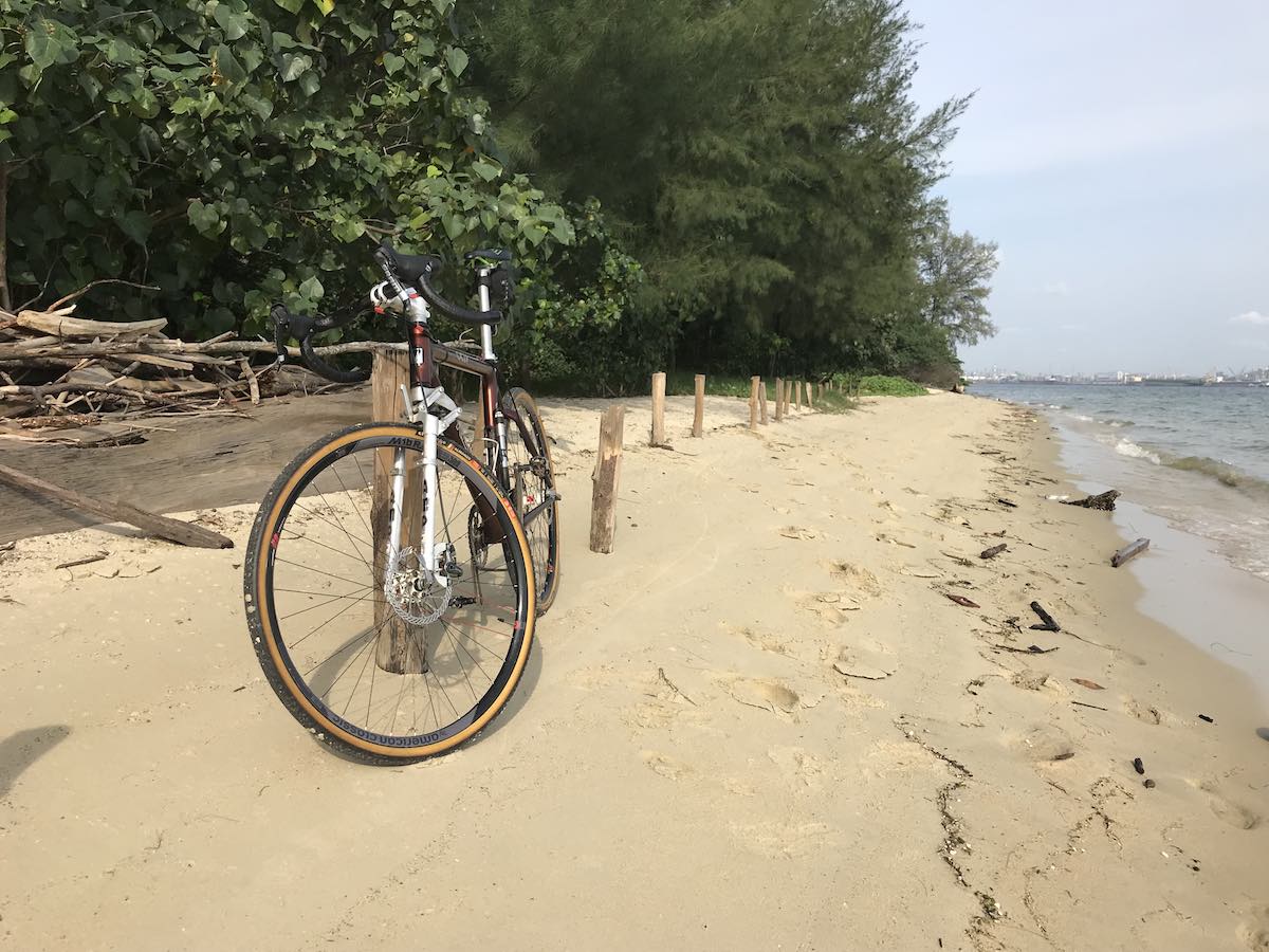 bikerumor pic of the day coney island singapore bicycle on a narrow sandy beach with thick green trees behind.