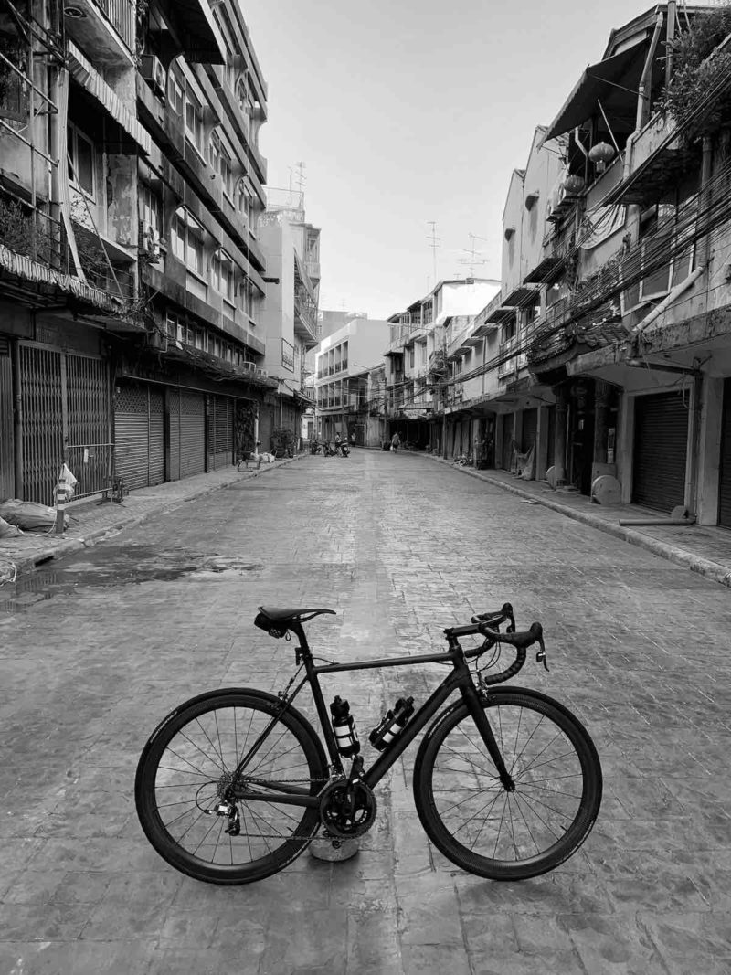 bikerumor pic of the day black and white photo of a bicycle on an empty street in Bangkok, Thailand.