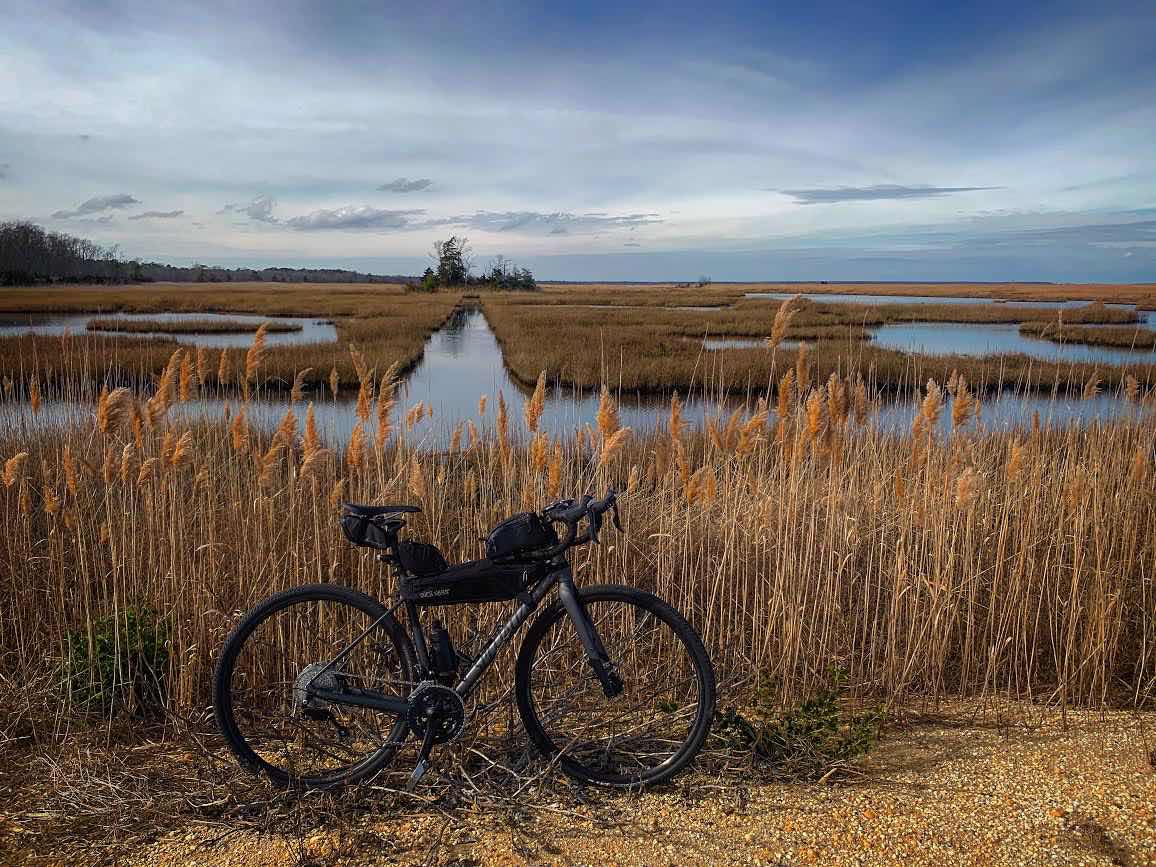bikerumor pic of the day Lester S MacNamara Reserve, Tuckahoe, new jersey. black specialized bicycle with packs sitting in front of wetlands and brown marsh grasses.