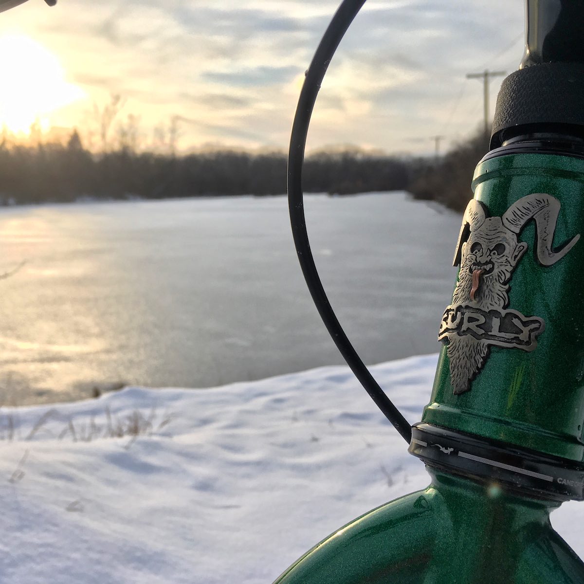 surly krampus headbadge looking out over the semi frozen lake and snowy bank at Homewood Izaak Walton Preserve, Homewood, Illinois.