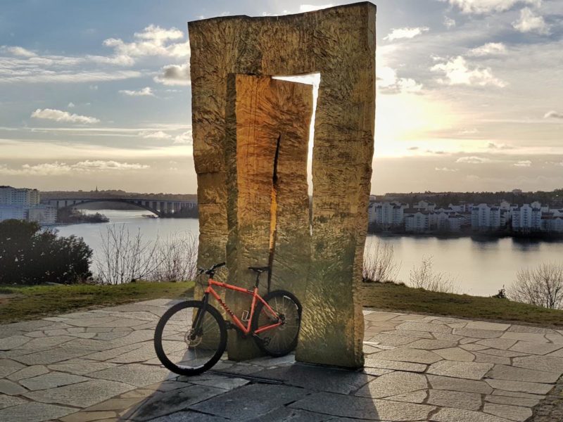 bikerumor pic of the day orange mountain bike in a park by the water under a lake rectangular gate like sculpture in solna, sweden.
