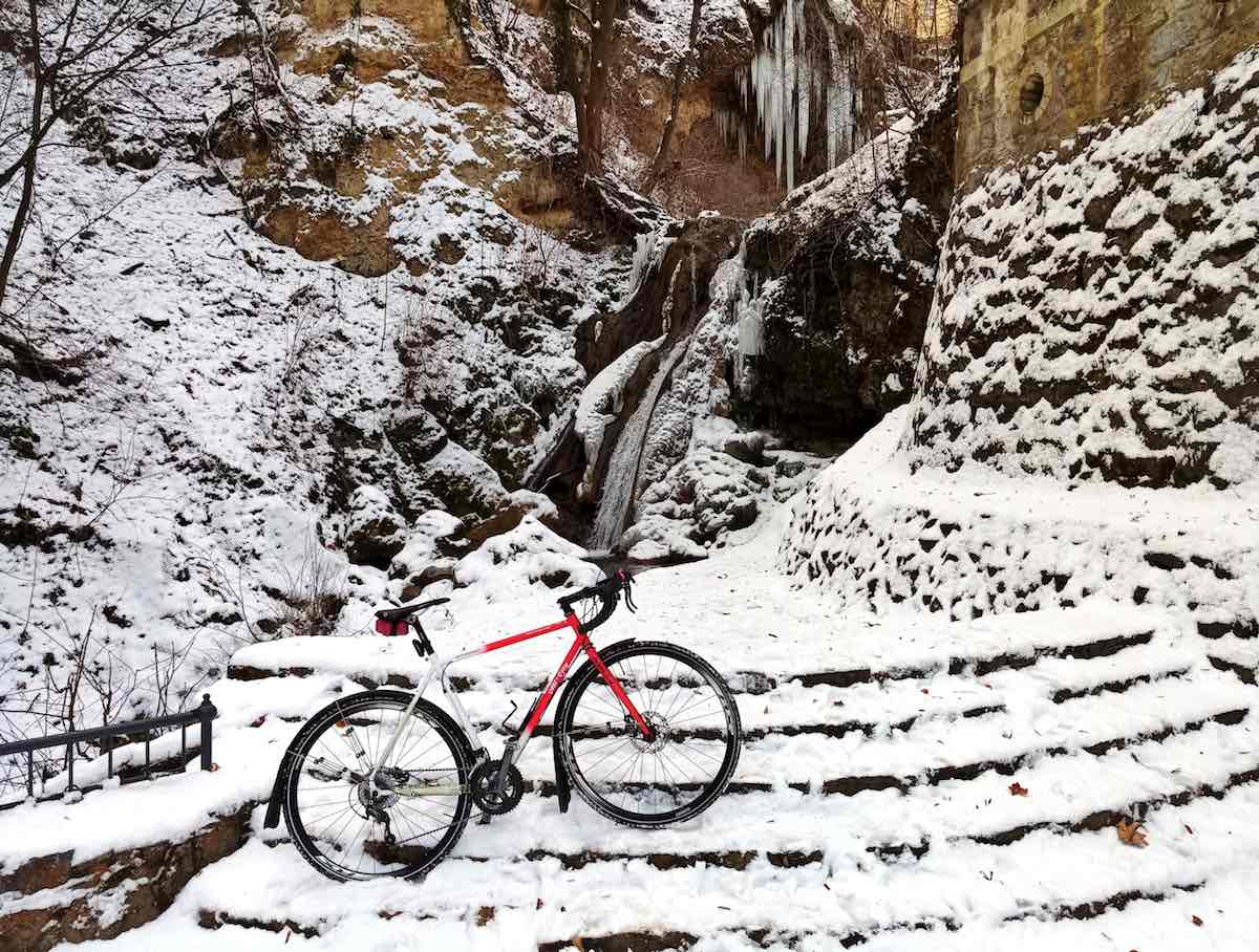 bikerumor pic of the day bicycle on steps leading up to a frozen waterfall with snow surrounding it on the ground and behind Lillafüred Falls near Miskolc, Hungary
