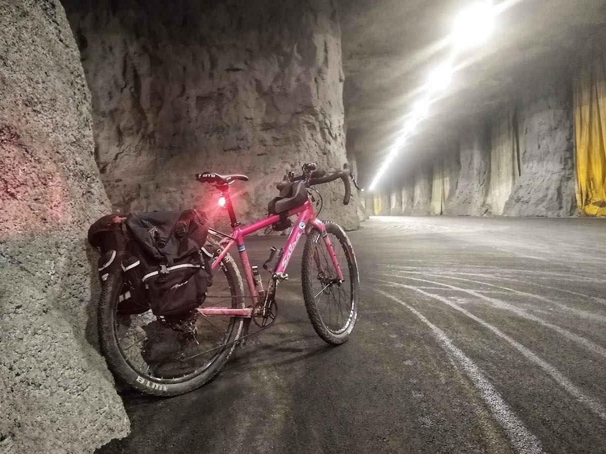 bikerumor pic of the day springfield missouri in the underground salsa journeyman leaning against a cave wall looking down a very high and very long tunnel with bright overhead lighting.