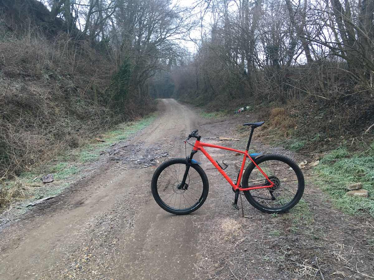 bikerumor pic of the day valle sauglio italy dirt road with red bicycle posed sideways, winter scrub brush on either side of the road.