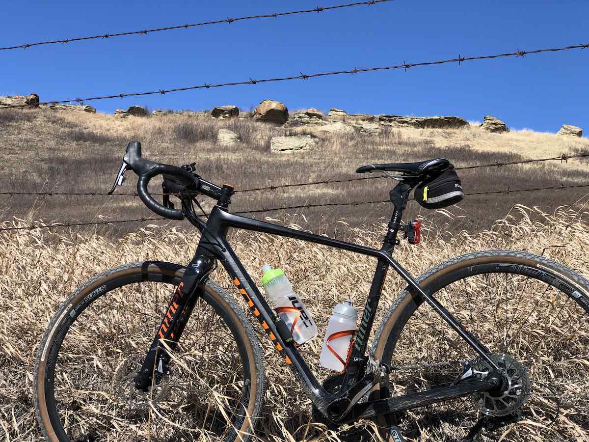 bikerumor pic of the day niner gravel bike bicycle leaning against a barbed wire fence beside a brown field that leads up to a bright blue sky.