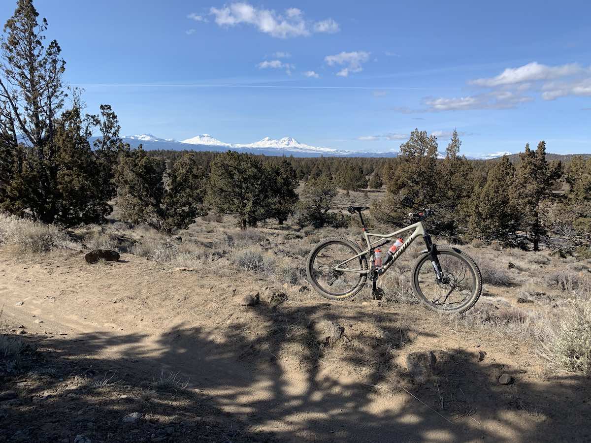 bikerumor pic of the day mountain bike posed on the maston trail system in central oregon, dry brush with low green pines in the distance with snow capped mountains on the horizon.