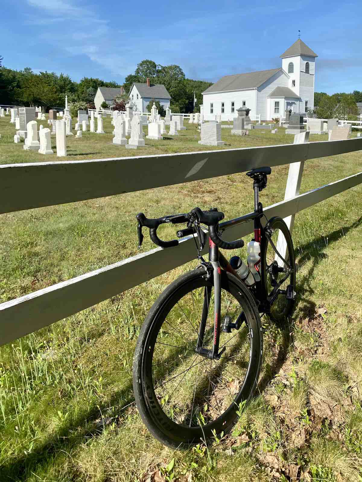 bikerumor pic of the day bicycle leaning against fence surrounding a new england church and cemetery.