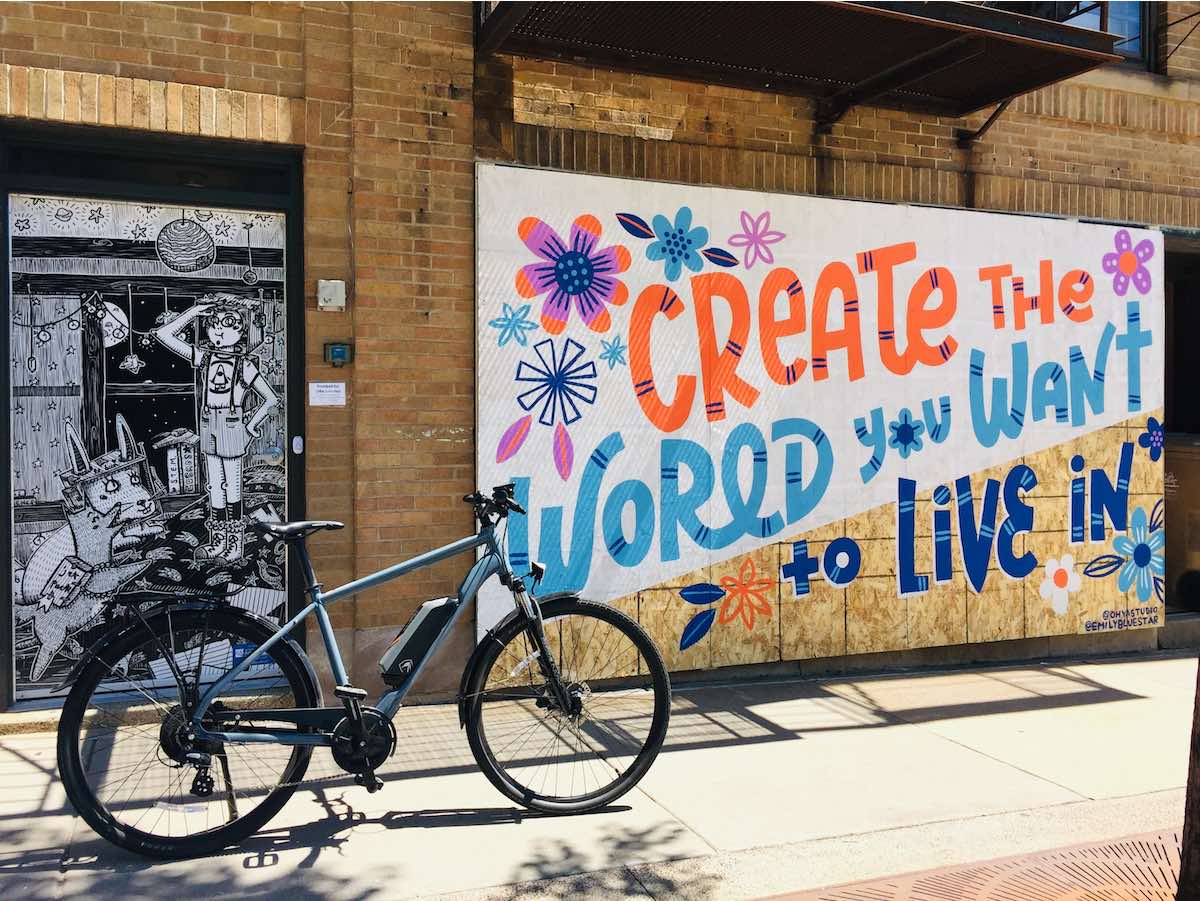 bikerumor pic of the day bike in front of window boards painted with create the world you want to live in downtown wisconsin, emily balsley