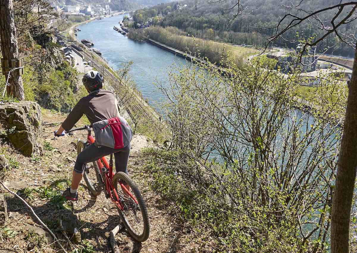 bikerumor pic of the day Marche-les-Dames belgium cyclist on path on edge of cliff along a river.