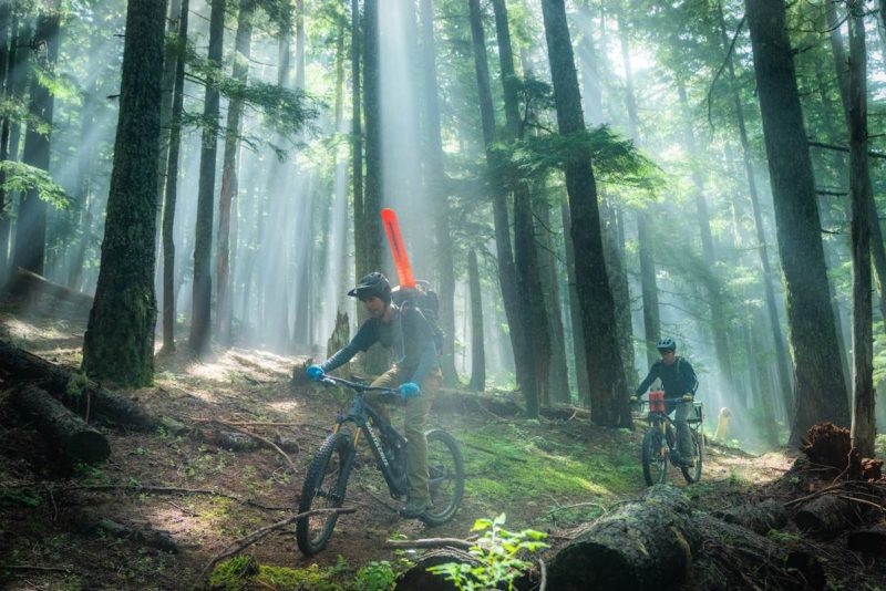 bikerumor pic of the day mountain bike trail work in the Gifford Pinchot Forest cyclists carry trail gear through the dense forest.
