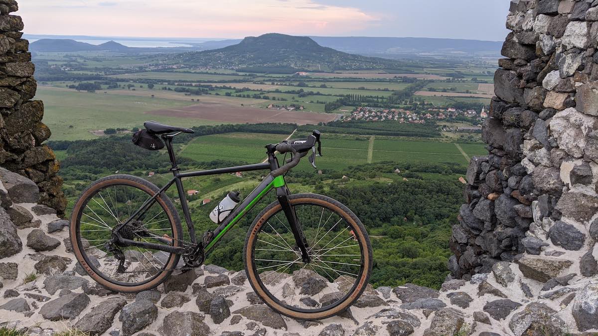 bikerumor pic of the day bicycle on the ruins of csobanc castle in hungary looking out over fields and a hill in the distance.