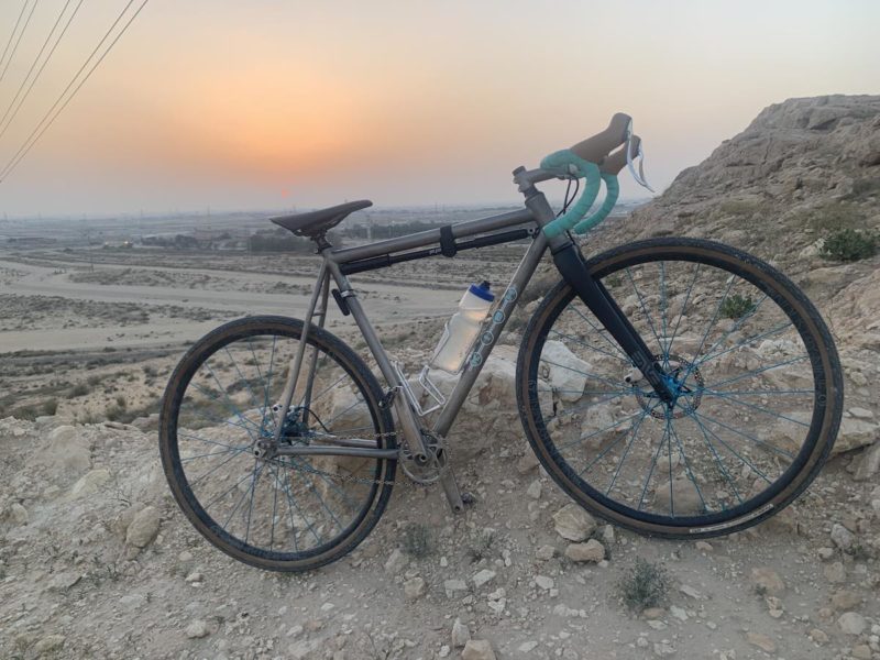 Bikerumor pic of the day kish bicycle in saudi arabia leaning on a dirt and rock incline with orange hazy sunset in the background