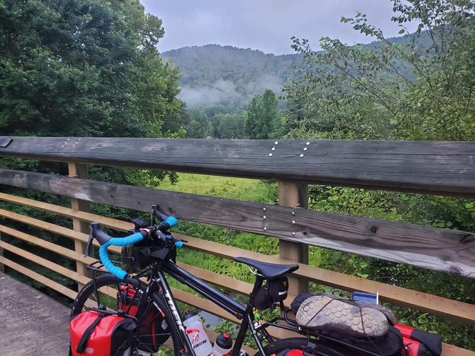 bikerumor pic of the day touring along the silver comet trail a bike leans against a wood railing overlooking a lush green landscape.