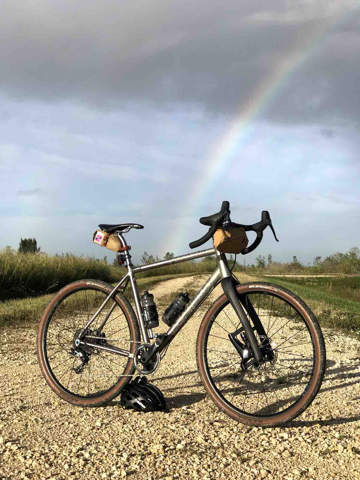 Bikerumor pic of the day lynskey bicycle in the middle of a gravel pathway with lowlands surrounding with cloudy skies and a rainbow in the distance