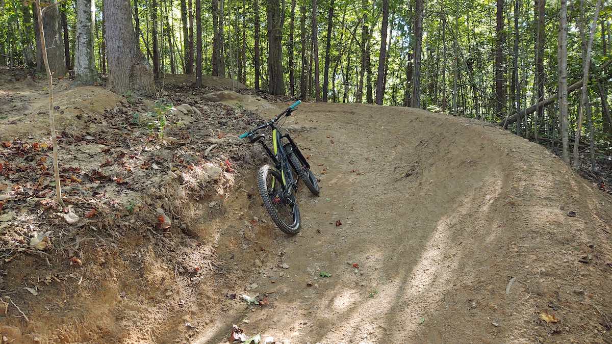 bikerumor pic of the day dirt berm with a bicycle leaning against it in the middle of the woods near travelers rest sc.