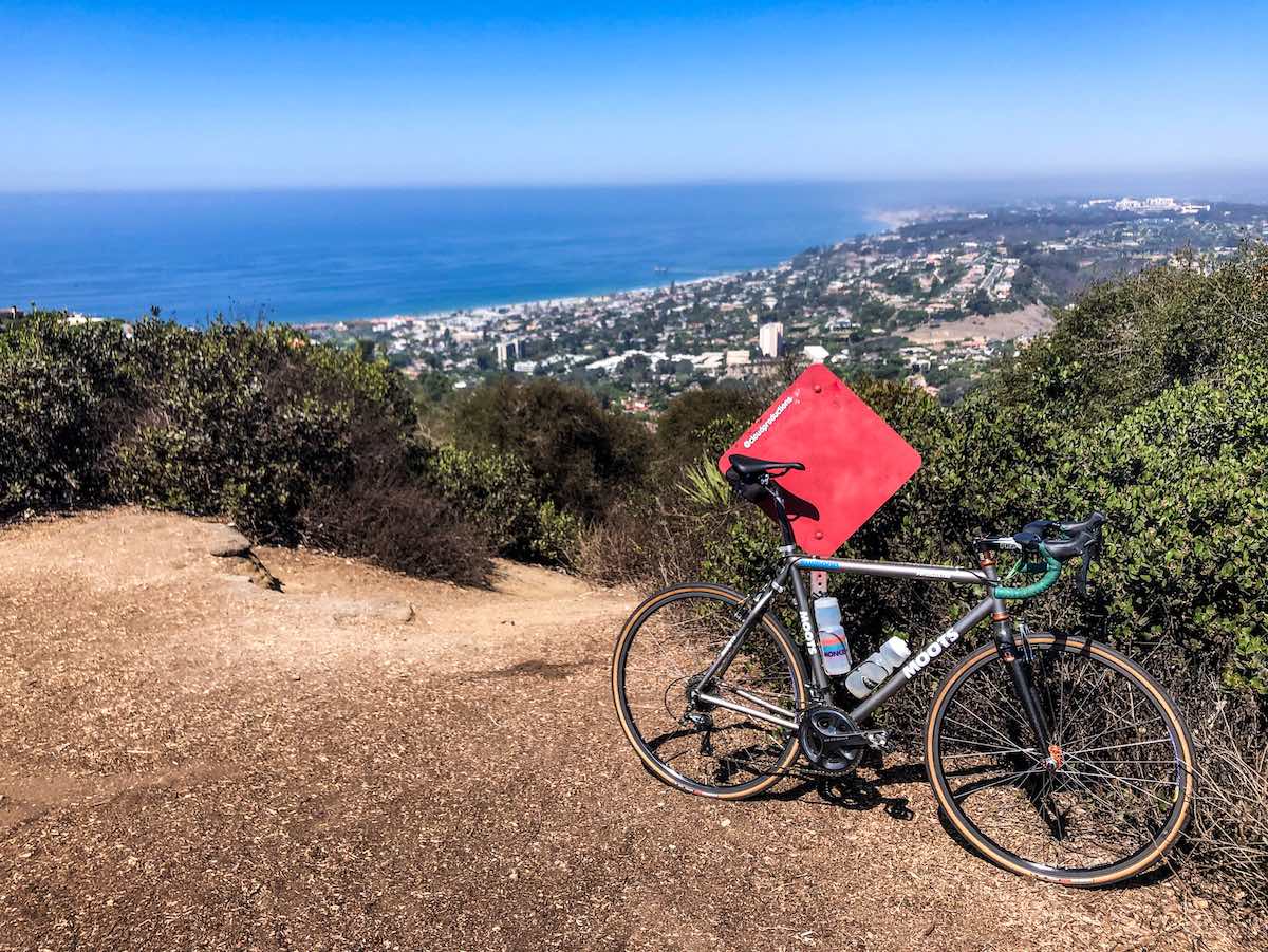 bikerumor pic of the day moots bicycle leaning against a red diamond sign on a sandy edge of a mountain overlooking a city by the sea la jolla california