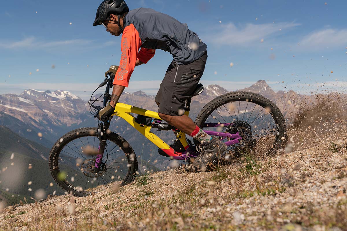 mountain bike rider drifts salsa cassidy enduro bike loose hard pack surface with mountainscape in background