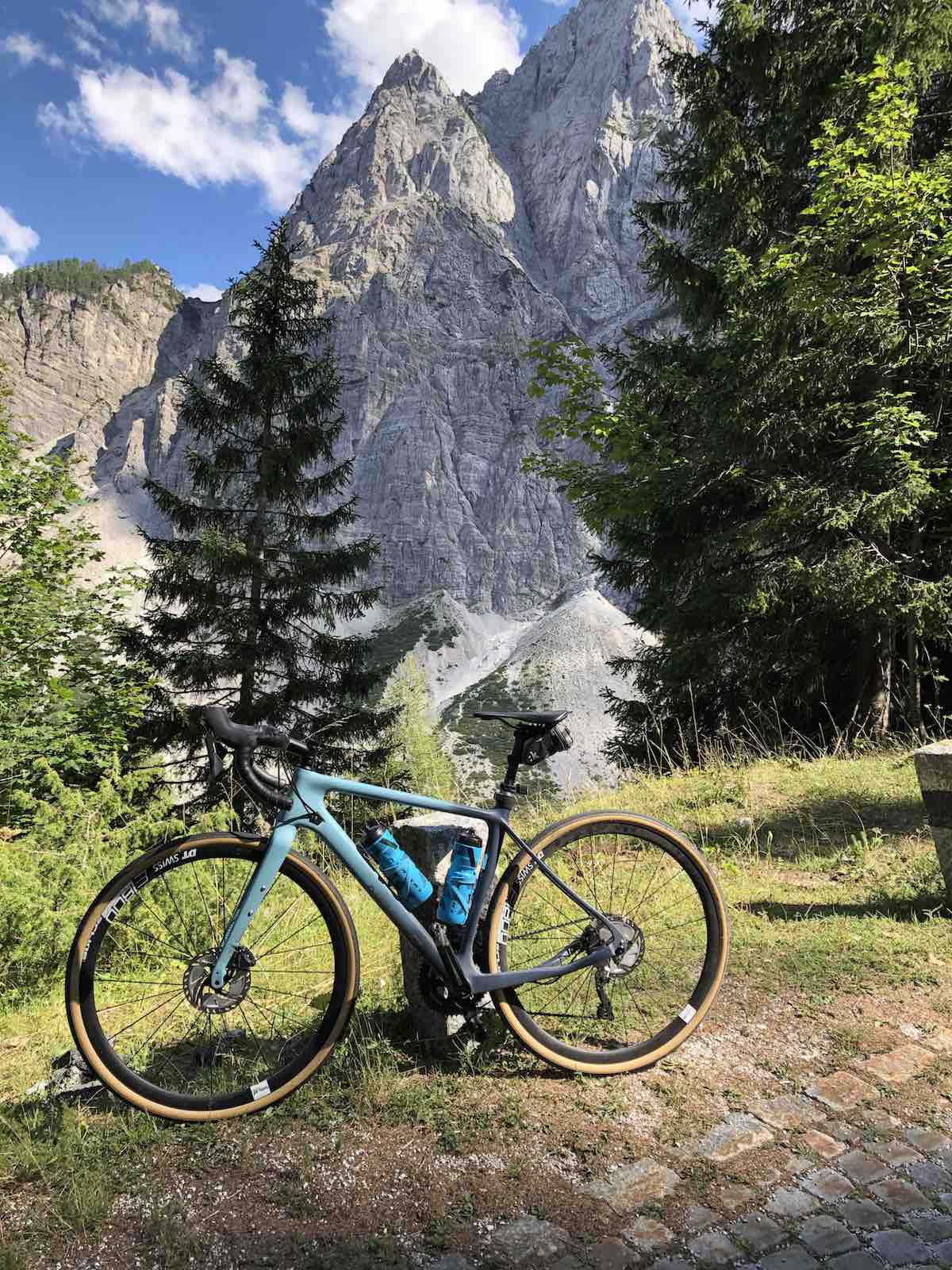 bikerumor pic of the day bicycle posed in front of the vrsic pass, large pine trees and the sharp rocky julien alps in slovenia