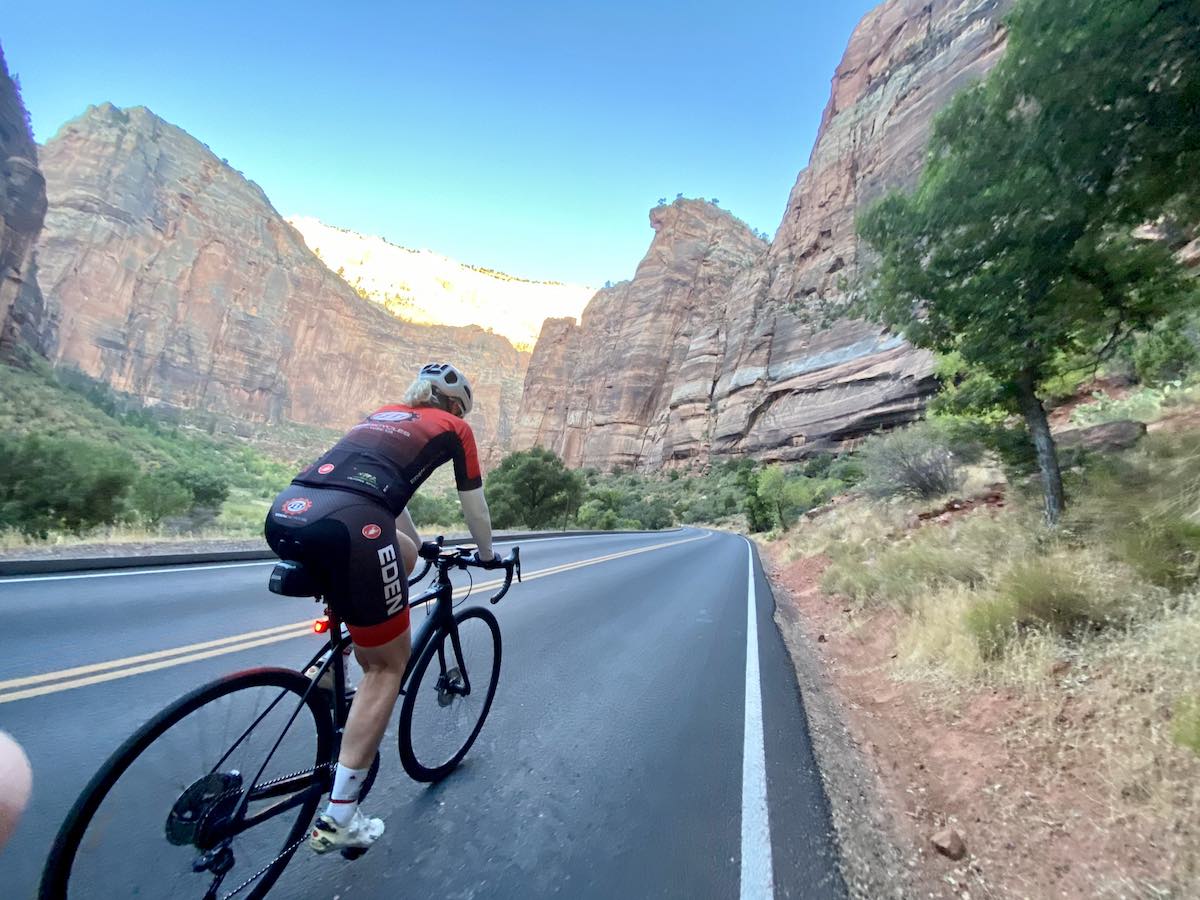 bikerumor pic of the day road cyclist riding through tall red and tan mountains in zion national park utah.