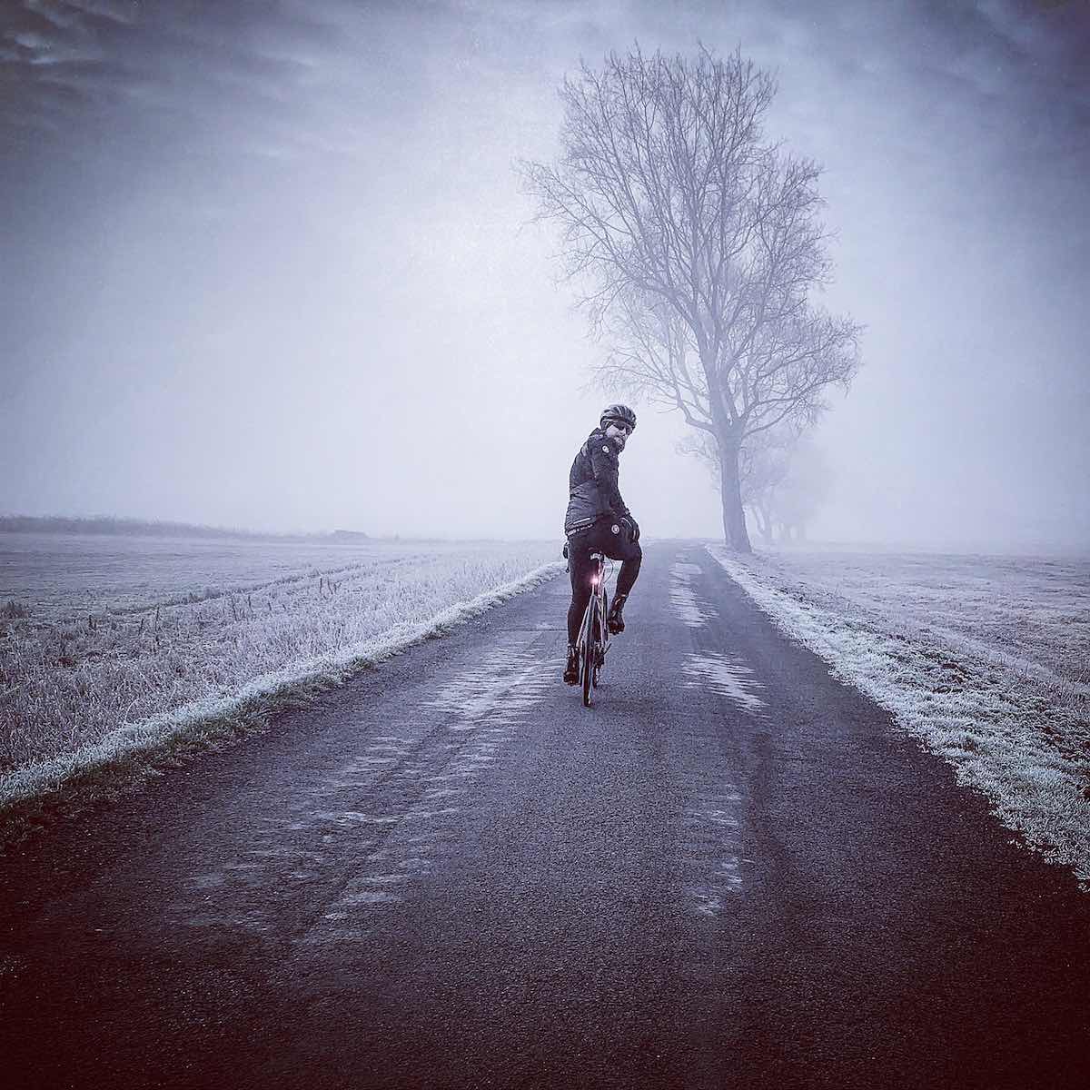 bikerumor pic of the day winter is coming Lancashire UK cyclist on dark road with frost on grass and tree.