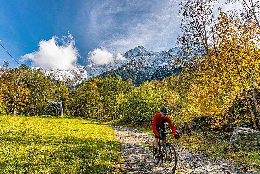 bikerumor pic of the day bike rider on a dirt path by a green lawn with trees and mont blanc in the distance.