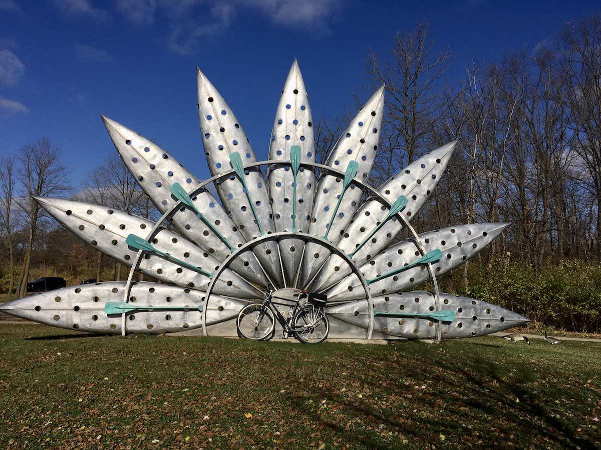 bikerumor pic of the day a bicycle leans against a large artwork of metal petals and painted oars in ann arbor michigan.