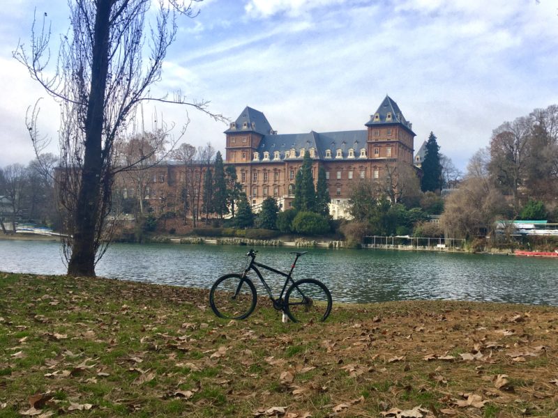 bikerumor pic of the day a bicycle on the land next to the river with a large building on the other side.