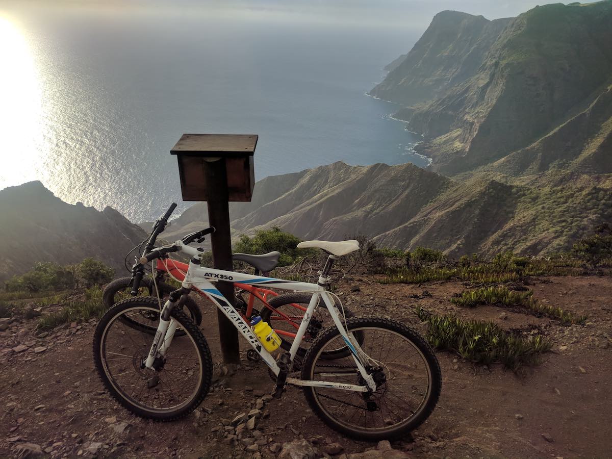 bikerumor pic of the day St Helena Island mountain bikes lean against a post box on the top of a mountain with steep cliffs overlooking the ocean.