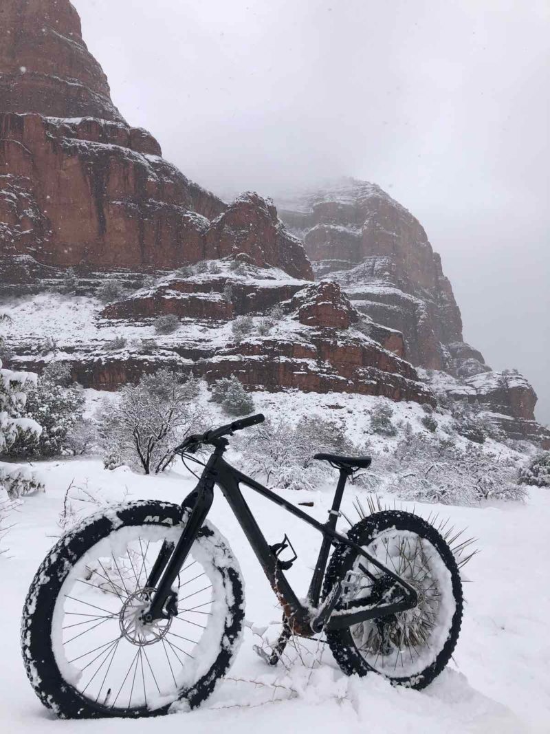 bikerumor pic of the day a mountain bike is in the snow below some red rock formations in sedona arizona the sky is grey and looks like it is snowing