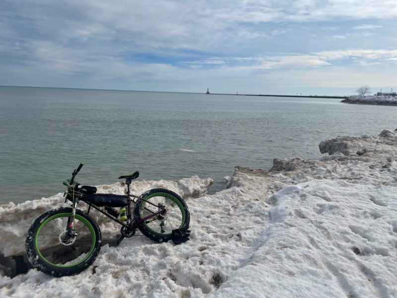 bikerumor pic of the day fat biking on lake michigan, snow and ice on the edge of the lake as a fat bike lays in the snow. the sky is large and mostly covered in clouds
