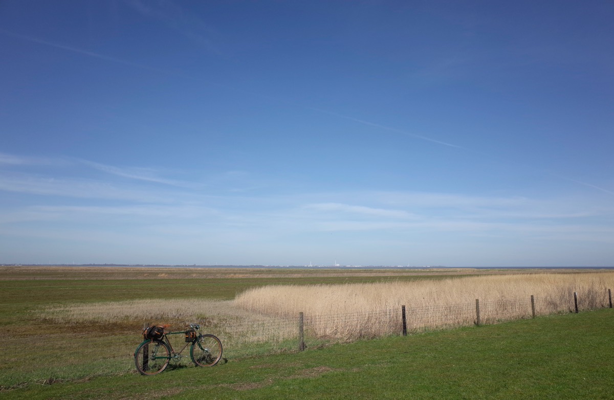bikerumor pic of the day a Göricke touring bicycle leans against a wire fence in a green field bordered with golden wheat and great big blue skies. a small town can be seen on the horizon.