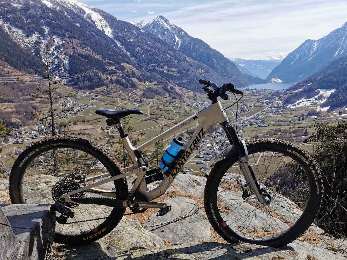 bikerumor pic of the day Val Poschiavo in Switzerland, a mountain bike is on a silk rock outcropping with snow capped alps in the far distance
