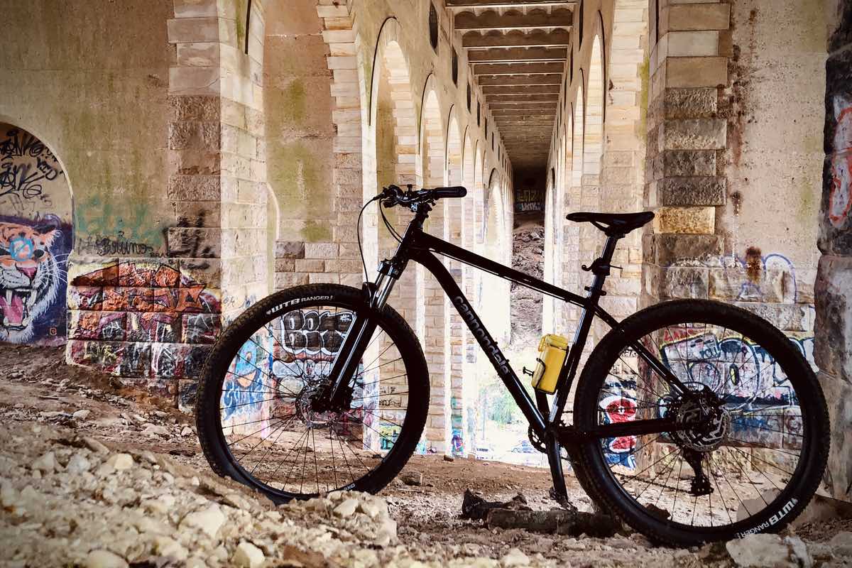 bikerumor pic of the day a bicycle is posed under a bridge that has graffiti spray painted on it.