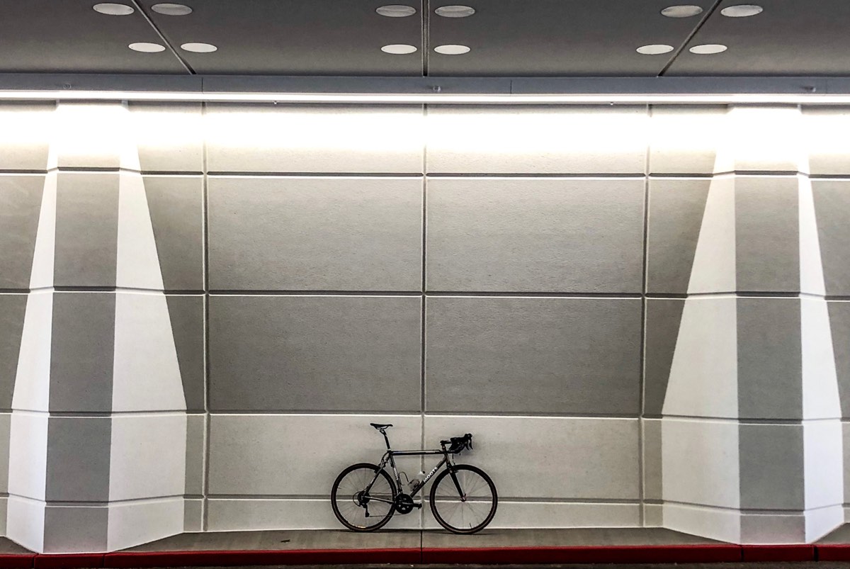 Bikerumor pic of the day a bicycle is leaning against the inside of a tunnel, the panels inside the tunnel are very geometric and the lights are such that it looks very three dimensional and grey.