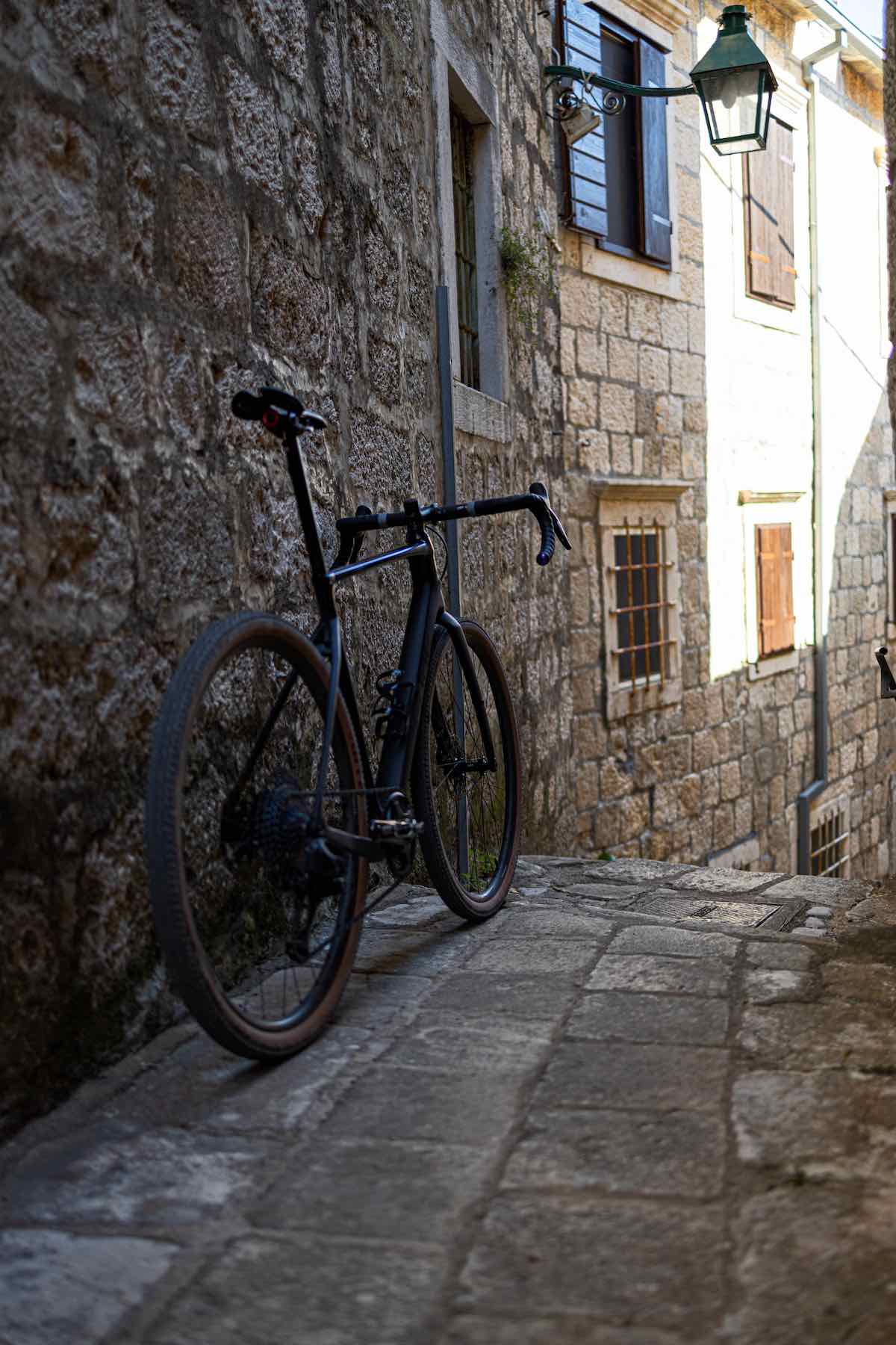 bikerumor pic of the day a road bike leans against a stone building in a narrow stone paved alley in croatia.