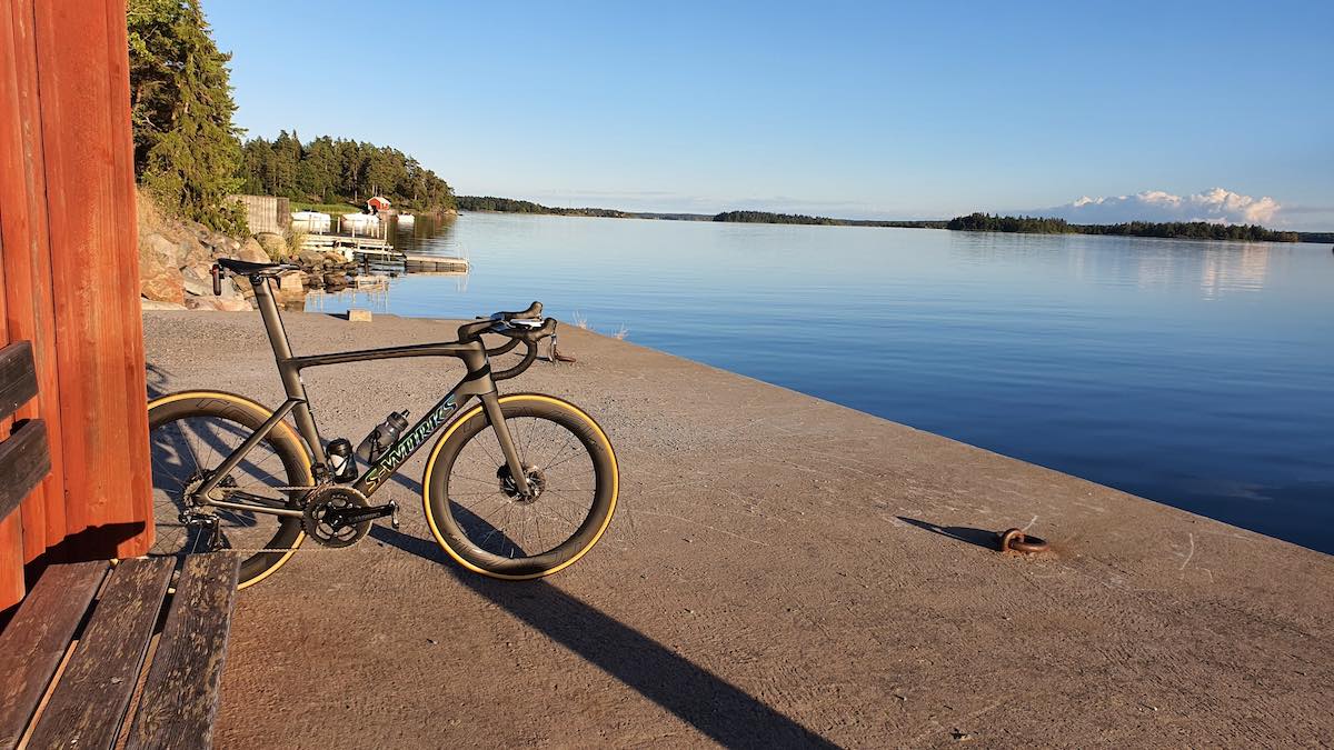 bikerumor pic of the day a specialized road bike leans against a small outbuilding on the edge of a pier looking out over smooth water, the sky is clear and reflecting off the water.