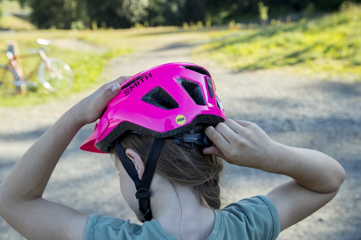 Girl adjusts the quick-fit knob on a Smith Wilder Jr. youth cycling helmet