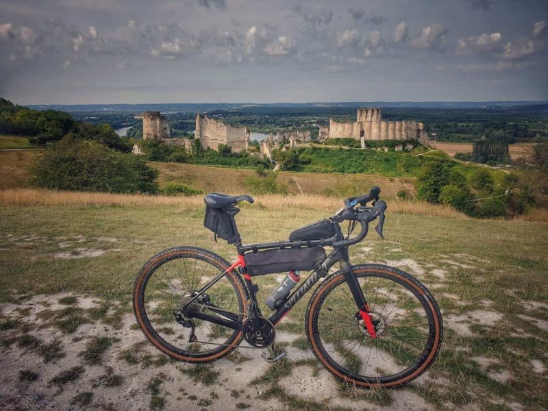 bikerumor pic of the day, a bicycle is on a low grassy hill overlooking a castle in ruins.